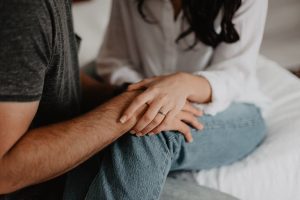 anonymous couple - woman wearing engagement ring holding man's hand