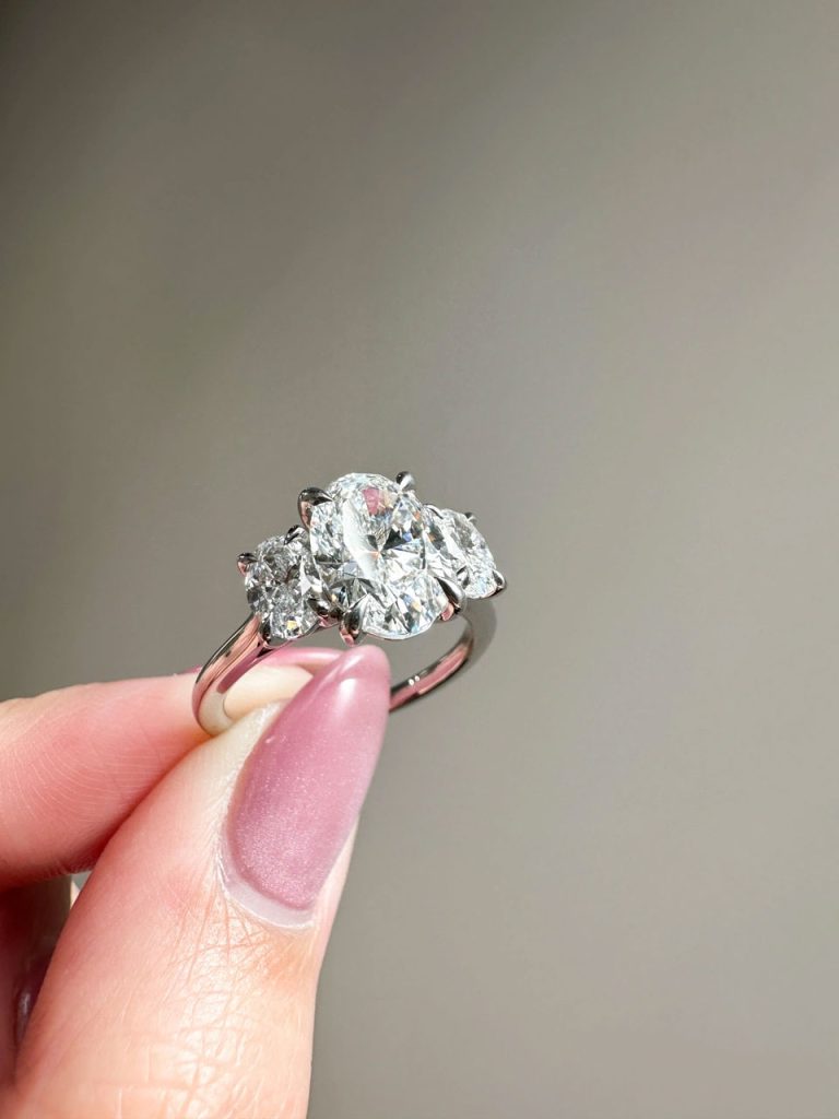 A stunning white gold ring with three oval diamonds, set with pointed prongs.